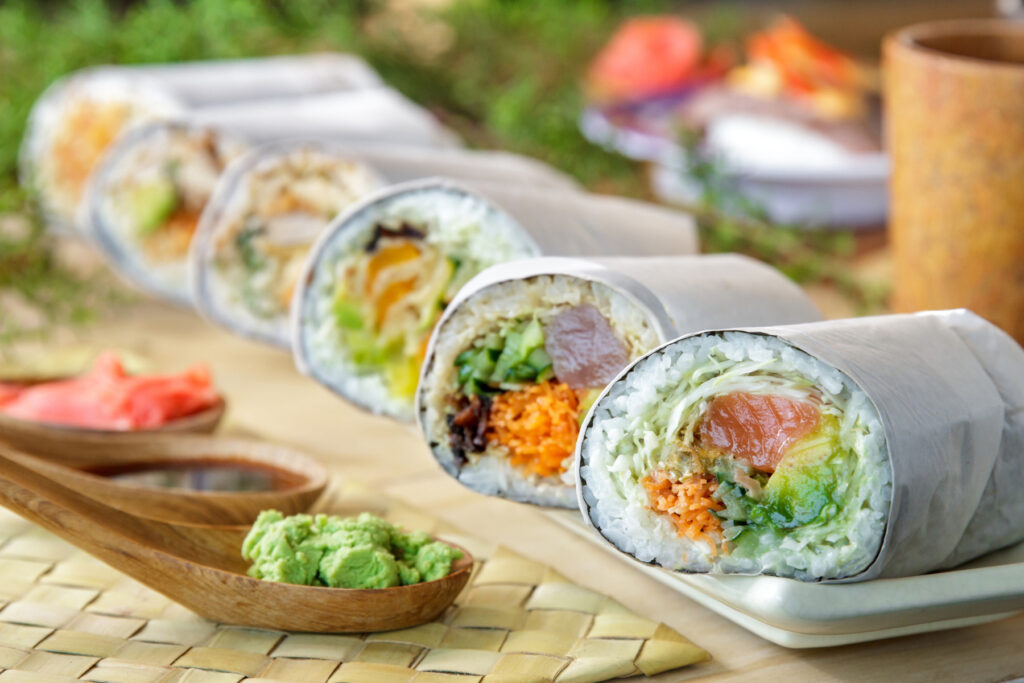 Japanese Flavors with Modern Twists - sushi burrito rolls served on a wooden plate with wasabi on the side